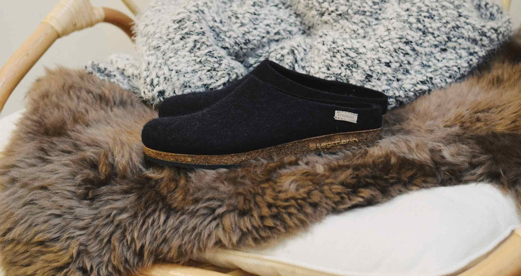 Stegmann clogs or slippers being shown off on a cozy chair.