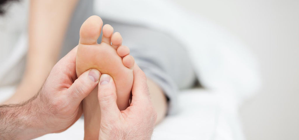 A podiatrist pushing on a patient's feet to determine their level of pain.