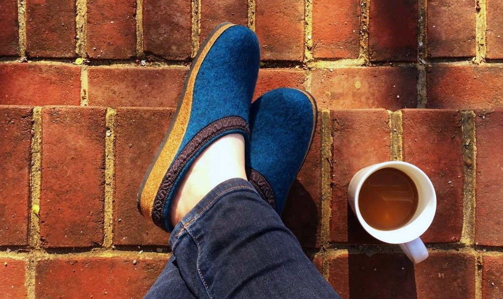Cozy turquoise wool clogs from beside a cup of coffee.