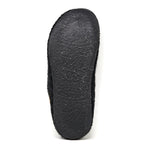 The image depicts the underside of a Men's Alpine Comfort Wool Slipper in black, featuring a subtly textured sole. The design suggests an anatomically shaped cork insole for enhanced comfort and support.