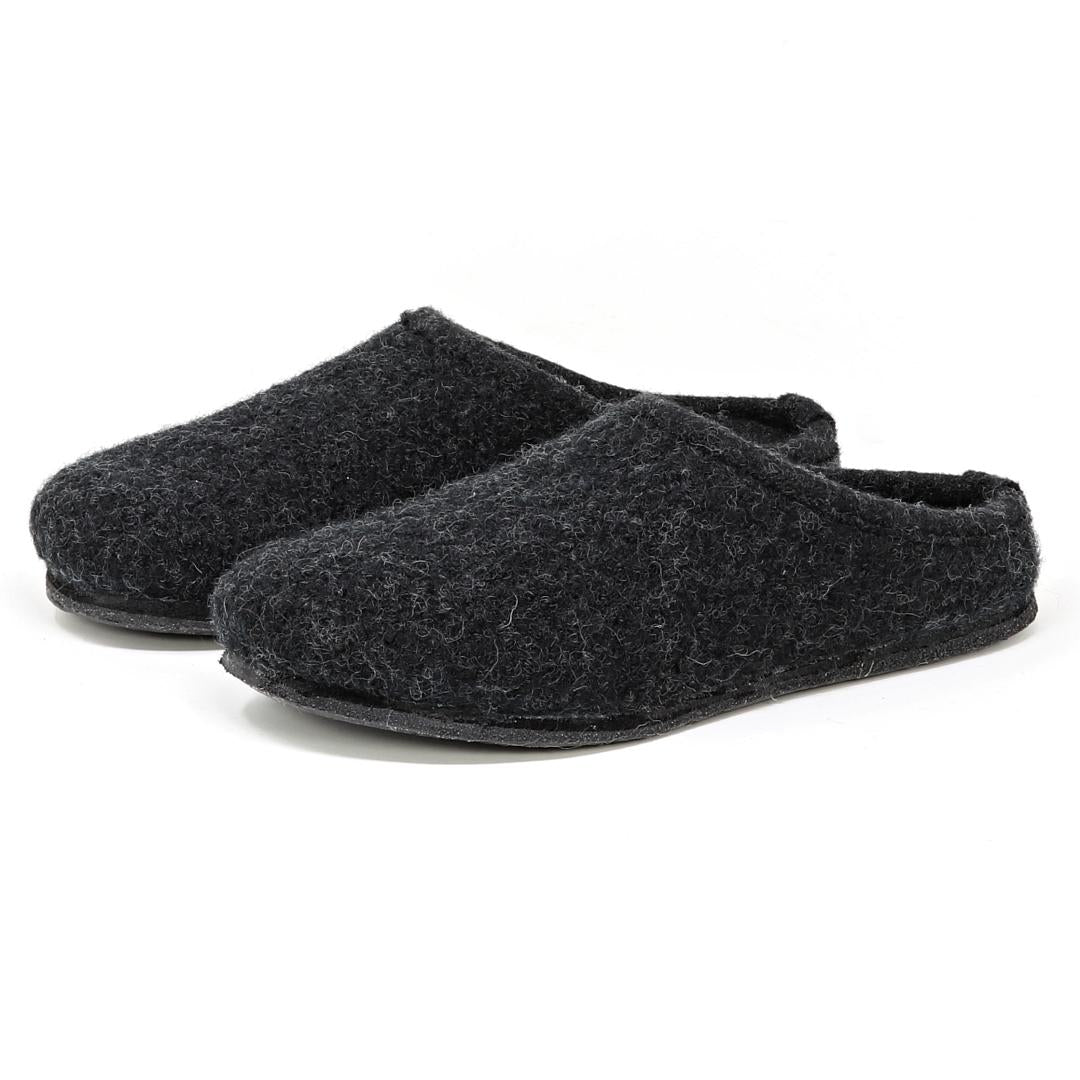 The Women's Alpine Comfort Wool Slipper, designed in dark gray with a soft merino wool upper and a comfy cork insole, showcases flat soles against a white backdrop.