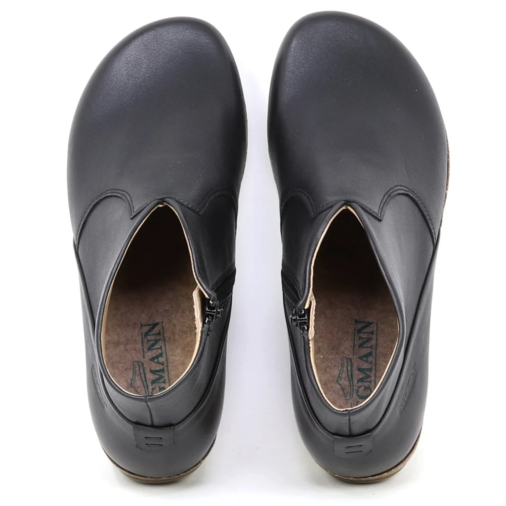 The Women's Leather Amalia Boot in black features a slip-on design with rounded toes, visible insoles, and side zippers, shown from a top-down view.