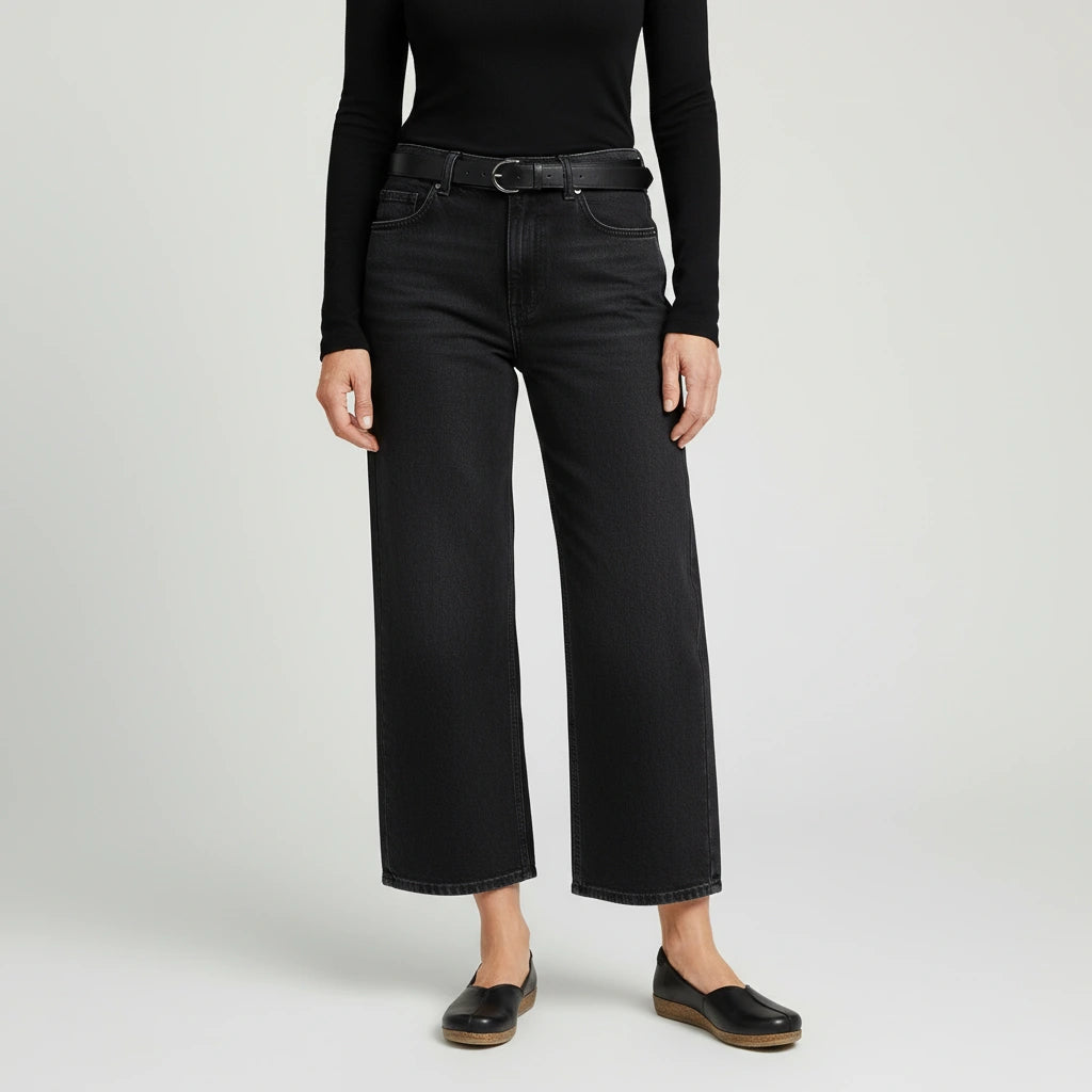 Person wearing a black long-sleeve top, black wide-leg jeans with the Women's Matching Leather Belt, and black slip-on shoes, standing against a plain light background.