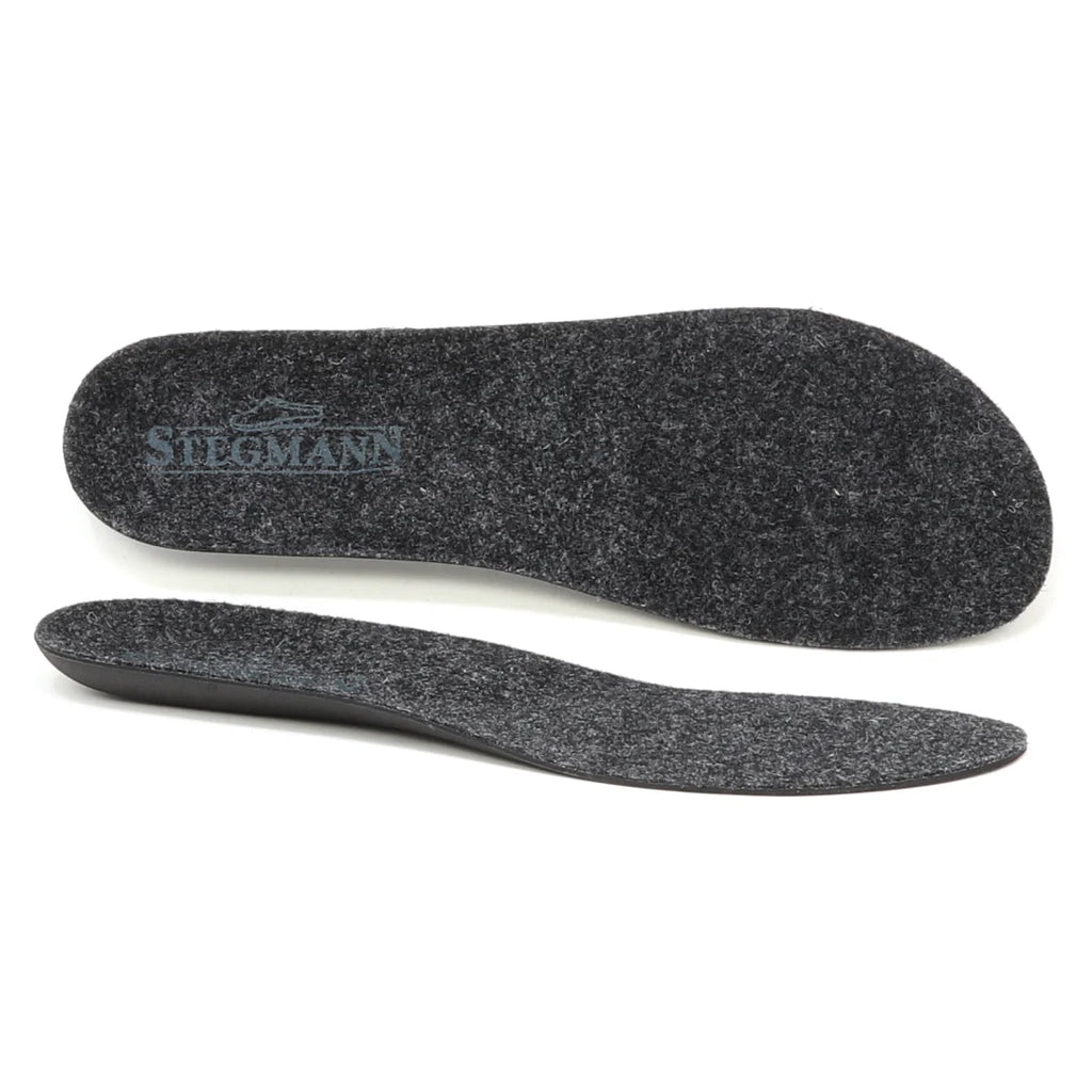 A pair of Women's Wool Contour Replacement Insoles w/Arch is displayed, with one insole shown from the top featuring the Stegmann logo and the other from the side to emphasize thickness, arch support, and durable wool felt material. These versatile inserts are designed to provide comfort and lasting wear every day.
