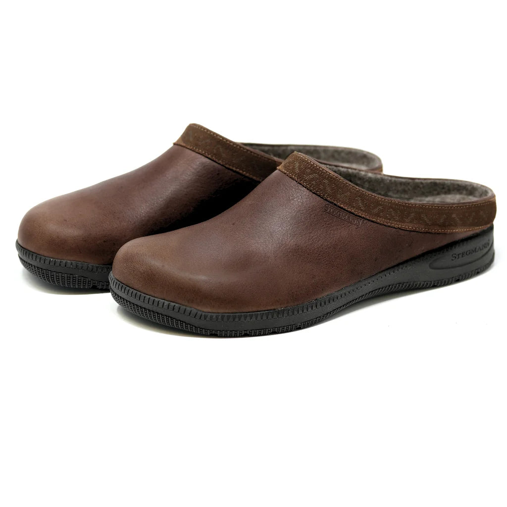 A pair of Men's Graz Leather Clog with Sport Sole in brown vegetable tanned leather and black textured recycled rubber soles, displayed against a white background.