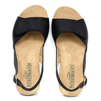 The Women's Clara Slingback Sandal features black open-toe design with ankle straps, a beige sole, and branded Stegmann insoles. These supportive sandals also offer a cushioned footbed for added comfort and are displayed flat on a white background.