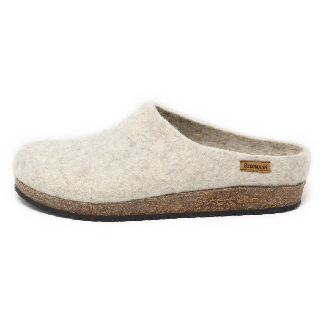 The Women's Eco Wool Clog is a beige slipper featuring a closed toe, open back, cork footbed sole, and a small rectangular Stegmann brand tag on the side.
