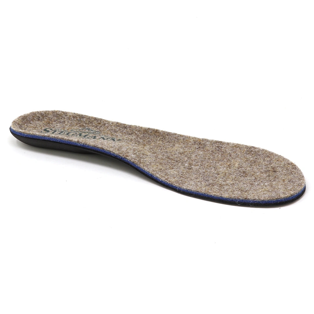 The Women’s Wool Contour Plus+ Replacement Insoles w/Arch are shown against a white background, featuring a brown felt material with a slightly curved shape and blue edging, designed to provide gentle arch support for enhanced comfort.