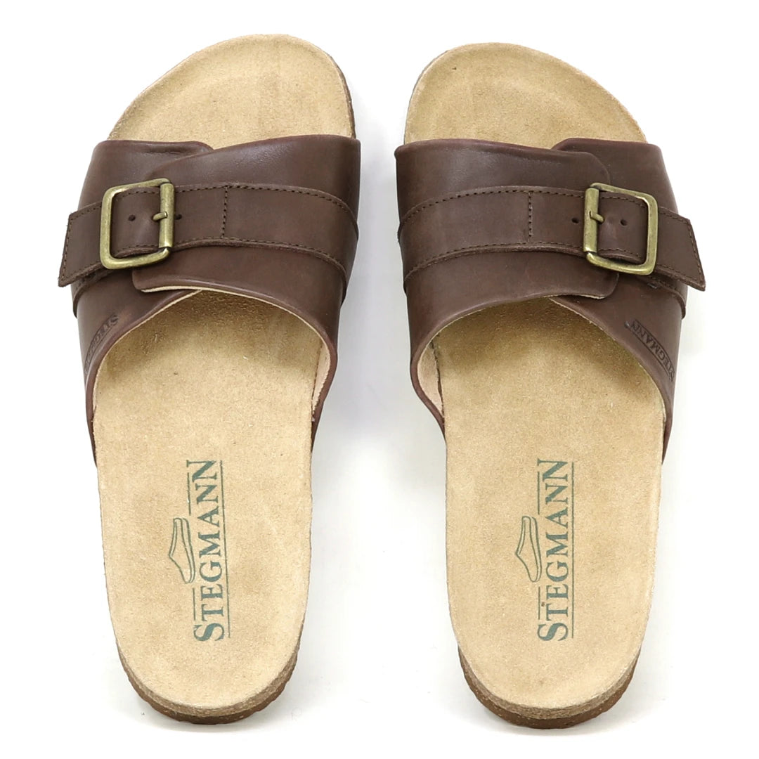 The Women's Ella Slide Sandal features brown leather adjustable straps, beige footbeds, a contoured cork footbed, and is branded with the STEGMANN logo.