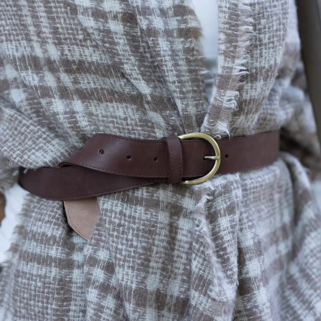 A close-up of a person wearing the Women’s Matching Leather Belt over a brown and white plaid textured coat.