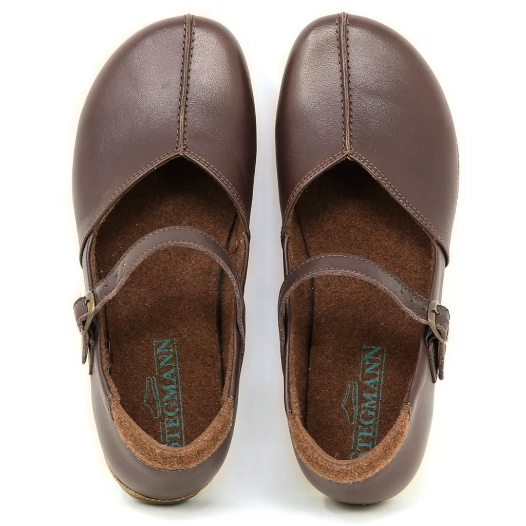 The Women's Eva Leather Mary-Jane features brown vegetable-tanned leather, buckle straps, and visible brand logos on the EVA insoles.