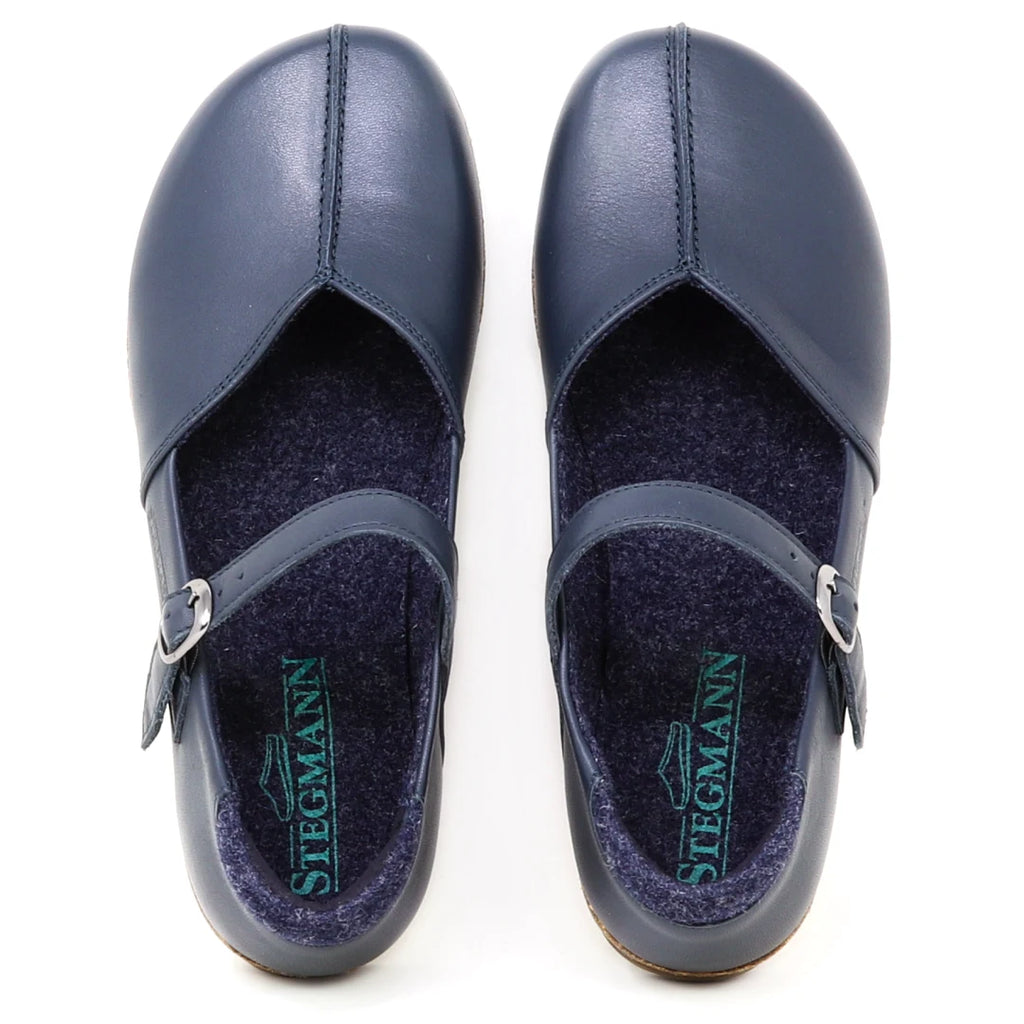 A pair of Women's Eva Leather Mary-Jane shoes in navy blue, featuring adjustable buckled straps and viewed from above to highlight the Stegmann logo on the insoles. Crafted as classic leather dress shoes, they offer a comfortable wide toe box for all-day wear.