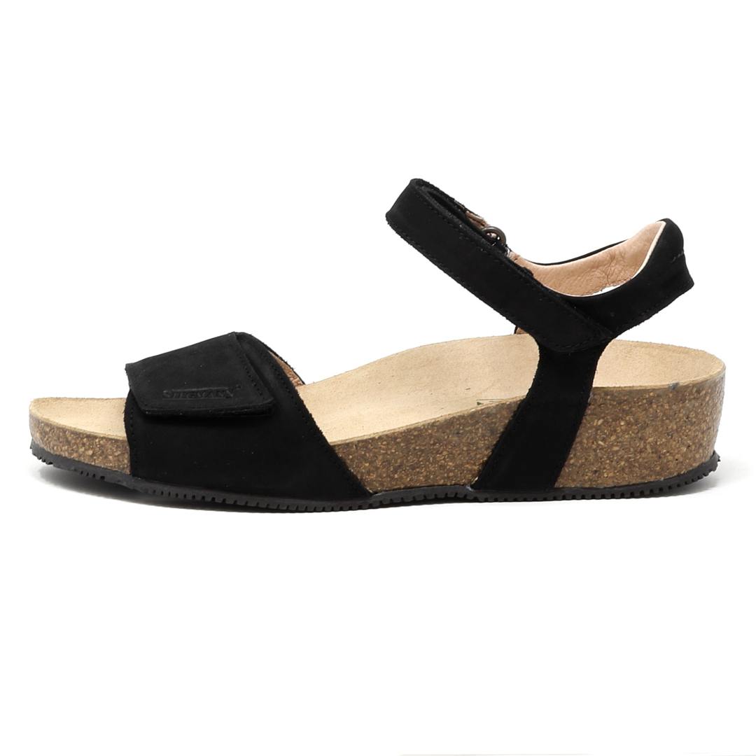The Women's Freya Leather Wedge Sandal is a black sandal with adjustable ankle and toe straps, featuring a cork-like sole and a recycled rubber traction outsole for enhanced stability.