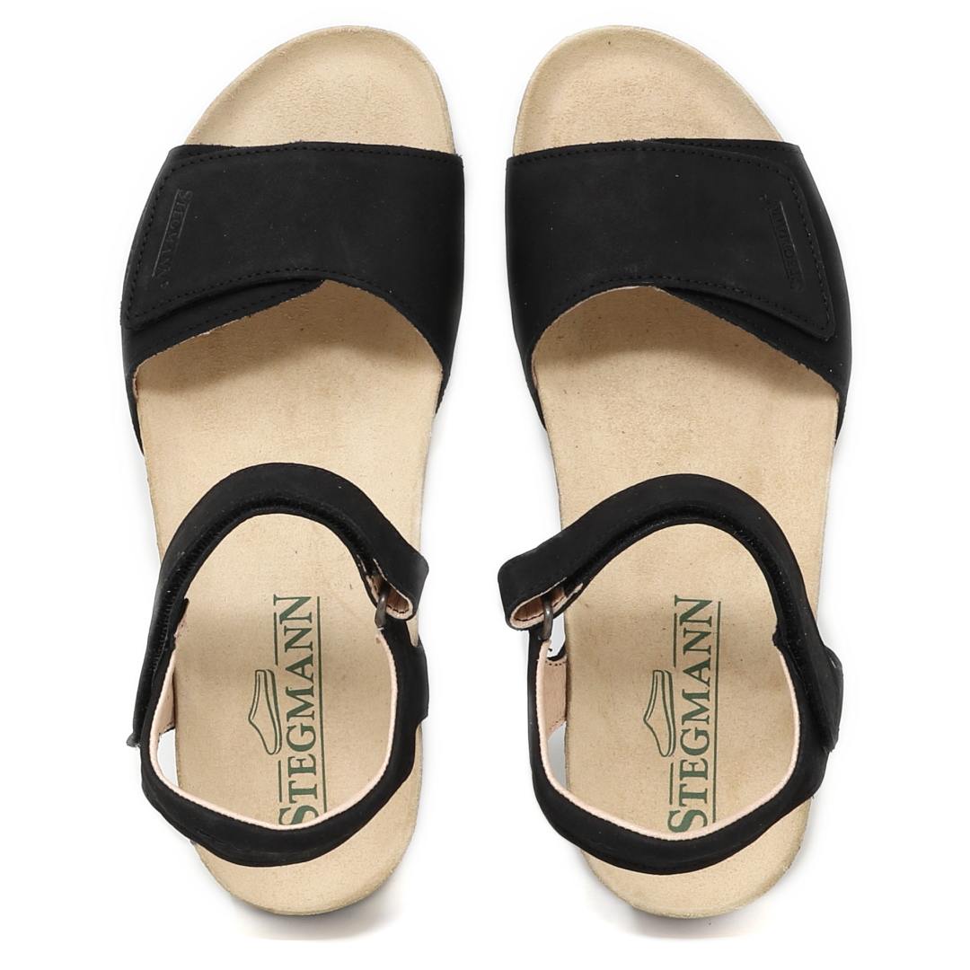 The Women's Freya Leather Wedge Sandal is a black strappy design with an ankle strap and beige sole, featuring the Stegmann logo on the insole and excellent arch support for comfort.