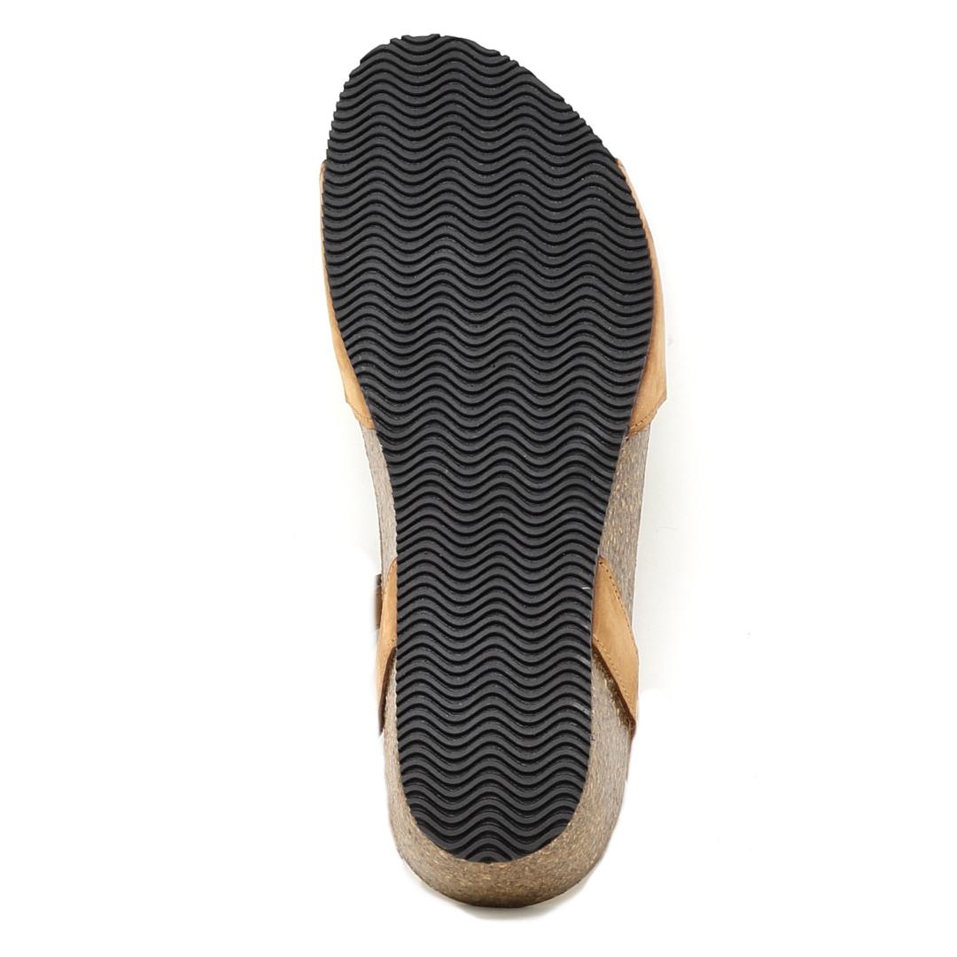 The image shows the bottom view of the Women's Freya Leather Wedge Sandal featuring a black, wavy-patterned rubber sole, tan leather upper straps, and adjustable velcro closures for comfort.