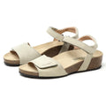 The Women's Freya Leather Wedge Sandal in beige showcases adjustable straps, open-toe design, cork soles, and recycled rubber traction outsoles on a white background.