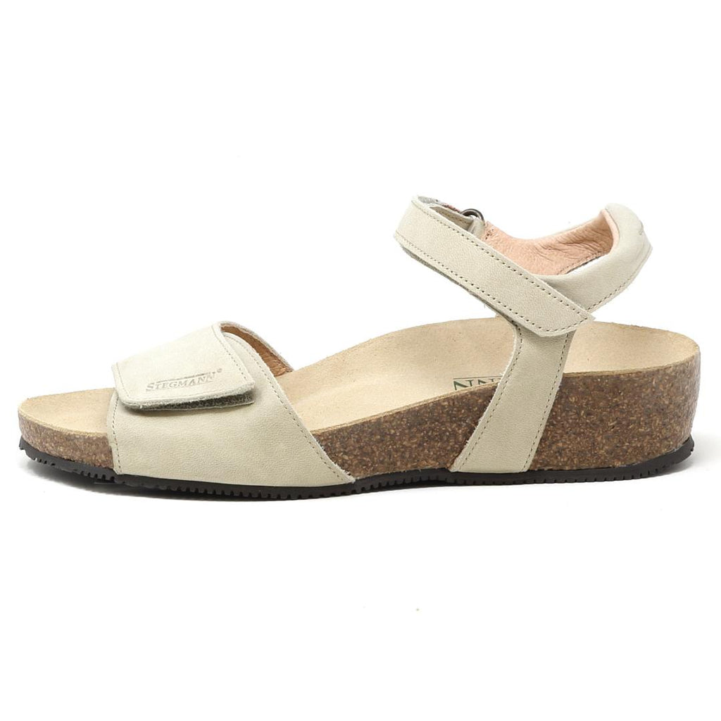 The Women's Freya Leather Wedge Sandal, shown in beige from the side, has a cork sole, adjustable ankle strap, and recycled rubber traction outsole.