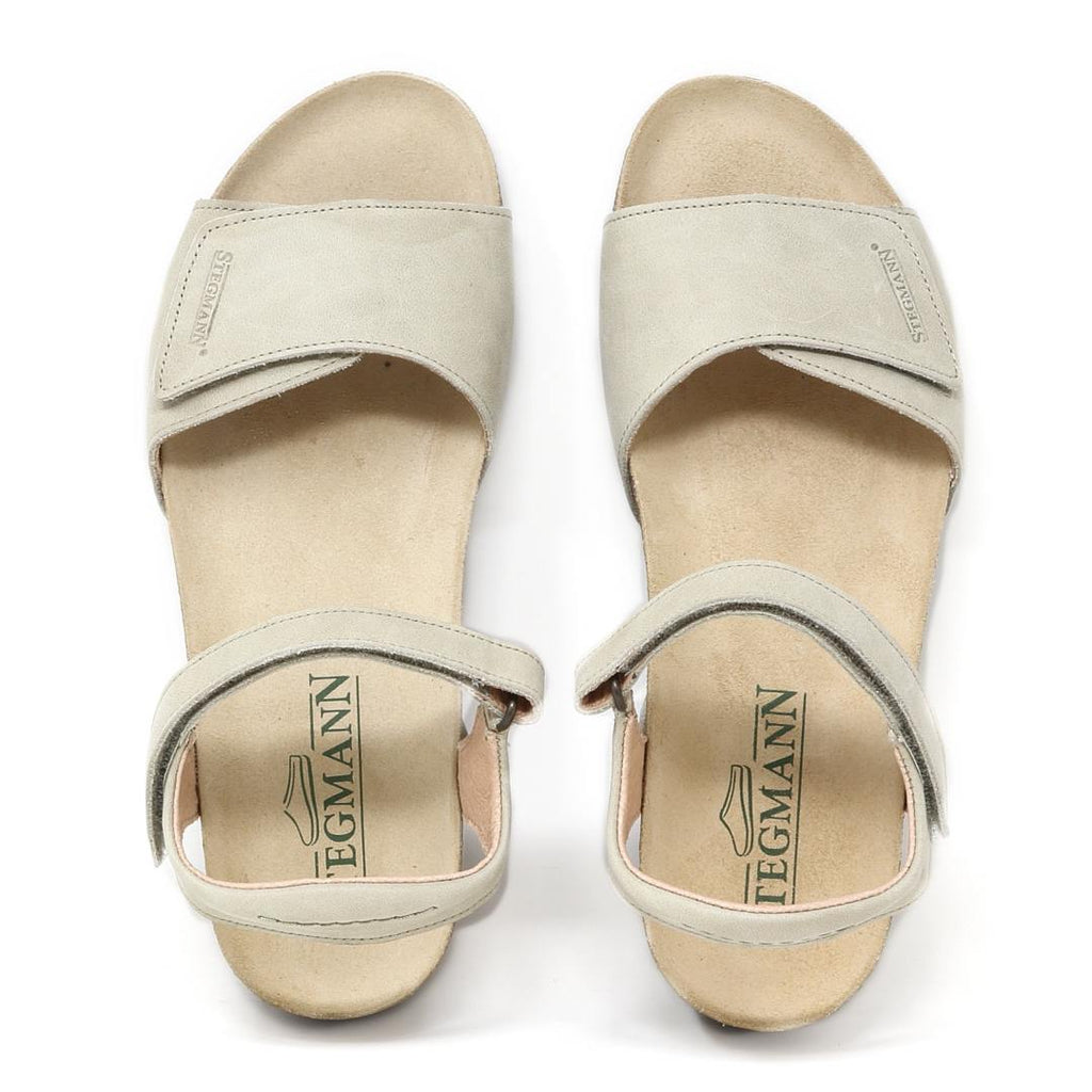 A pair of Women's Freya Leather Wedge Sandals in light beige with open toes and ankle straps, featuring a recycled rubber traction outsole for added grip and a "Tegmann" label on the insole.