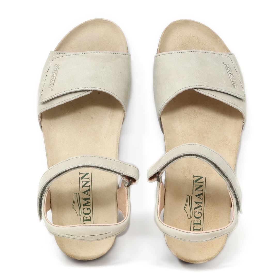 A pair of Women's Freya Leather Wedge Sandals in light beige with open toes and ankle straps, featuring a recycled rubber traction outsole for added grip and a "Tegmann" label on the insole.
