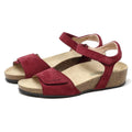The Women's Freya Leather Wedge Sandal, a pair of red suede sandals with adjustable ankle straps and cork platform soles, features recycled rubber traction outsoles. Positioned at an angle on a white background, these stylish strappy wedges offer both elegance and durability.
