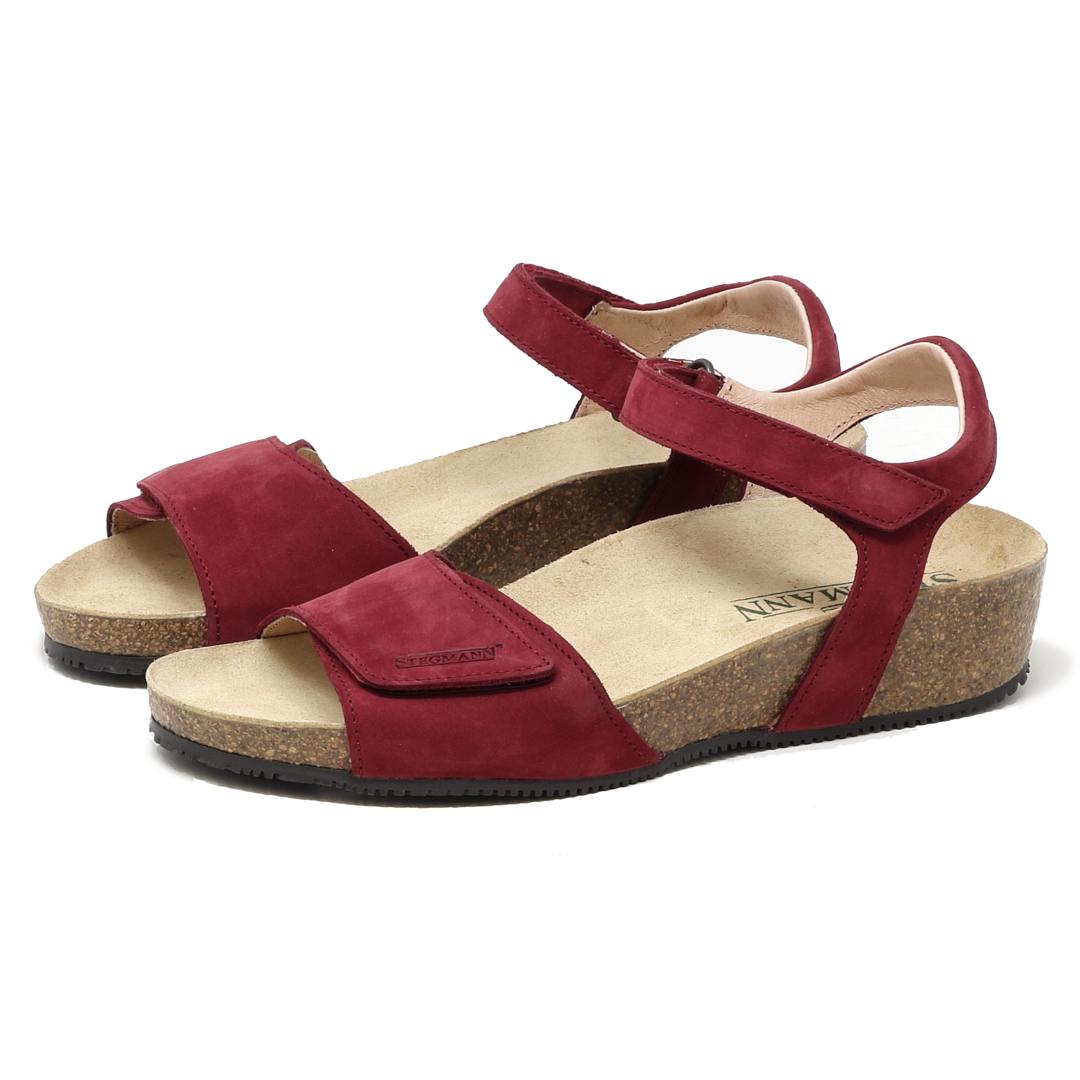The Women's Freya Leather Wedge Sandal, a pair of red suede sandals with adjustable ankle straps and cork platform soles, features recycled rubber traction outsoles. Positioned at an angle on a white background, these stylish strappy wedges offer both elegance and durability.