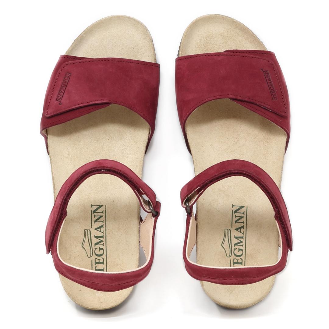 The Women's Freya Leather Wedge Sandal features red suede straps, adjustable ankle closures, and beige footbeds with "Stegmann" branding. These chic wedges have a recycled rubber traction outsole for enhanced stability.