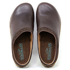 The Women's Graz Leather Clog is a pair of brown clogs with decorative trim and cork soles, designed for a bunion-friendly fit. Crafted from vegetable-tanned leather, "STEGMANN" is visible on the insole when viewed from above.
