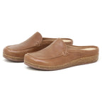 A pair of Women's Greta Leather Mule slip-on clogs in brown leather with closed toes and cork soles, featuring a shock-absorbing midsole, shown on a white background.