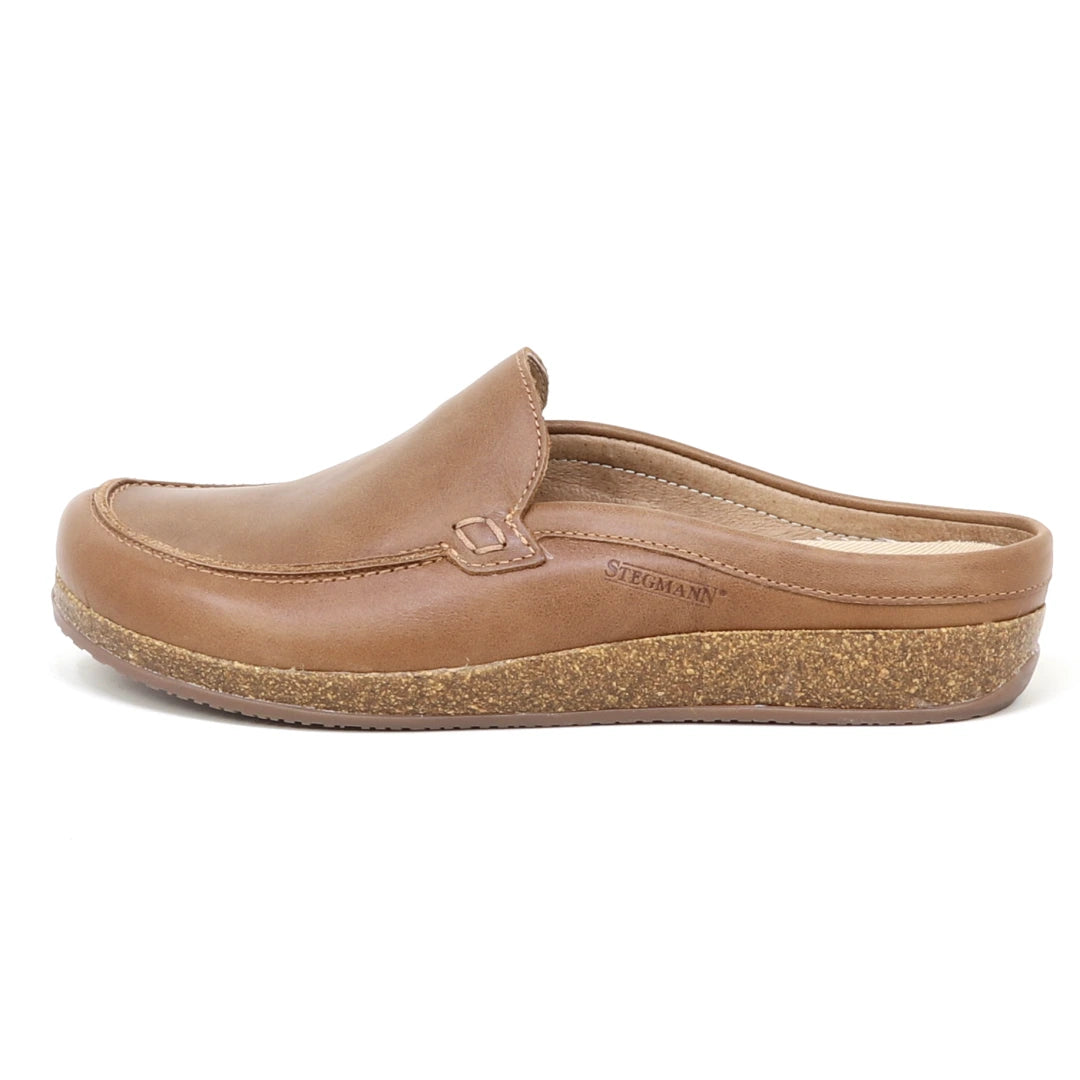 A brown leather Women's Greta Leather Mule slip-on shoe with a cork sole, displayed in profile view facing left. The brand name "Stegmann" is embossed on the side, and the design includes built-in arch support for enhanced comfort.