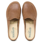 A pair of Women's Greta Leather Mule slip-on shoes in brown leather, featuring beige insoles with the Stegmann logo printed in green and providing excellent arch support.
