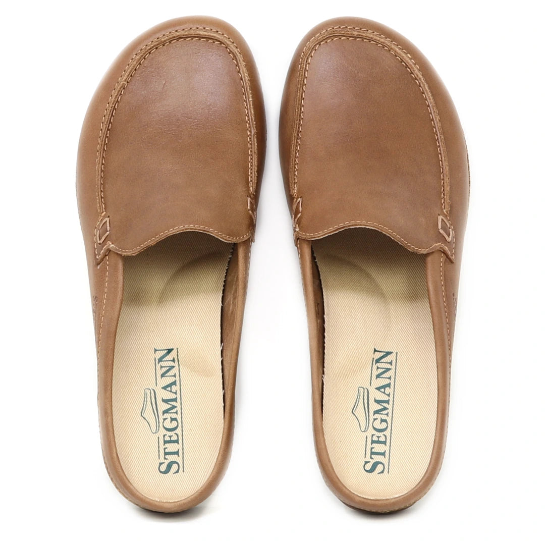 A pair of Women's Greta Leather Mule slip-on shoes in brown leather, featuring beige insoles with the Stegmann logo printed in green and providing excellent arch support.