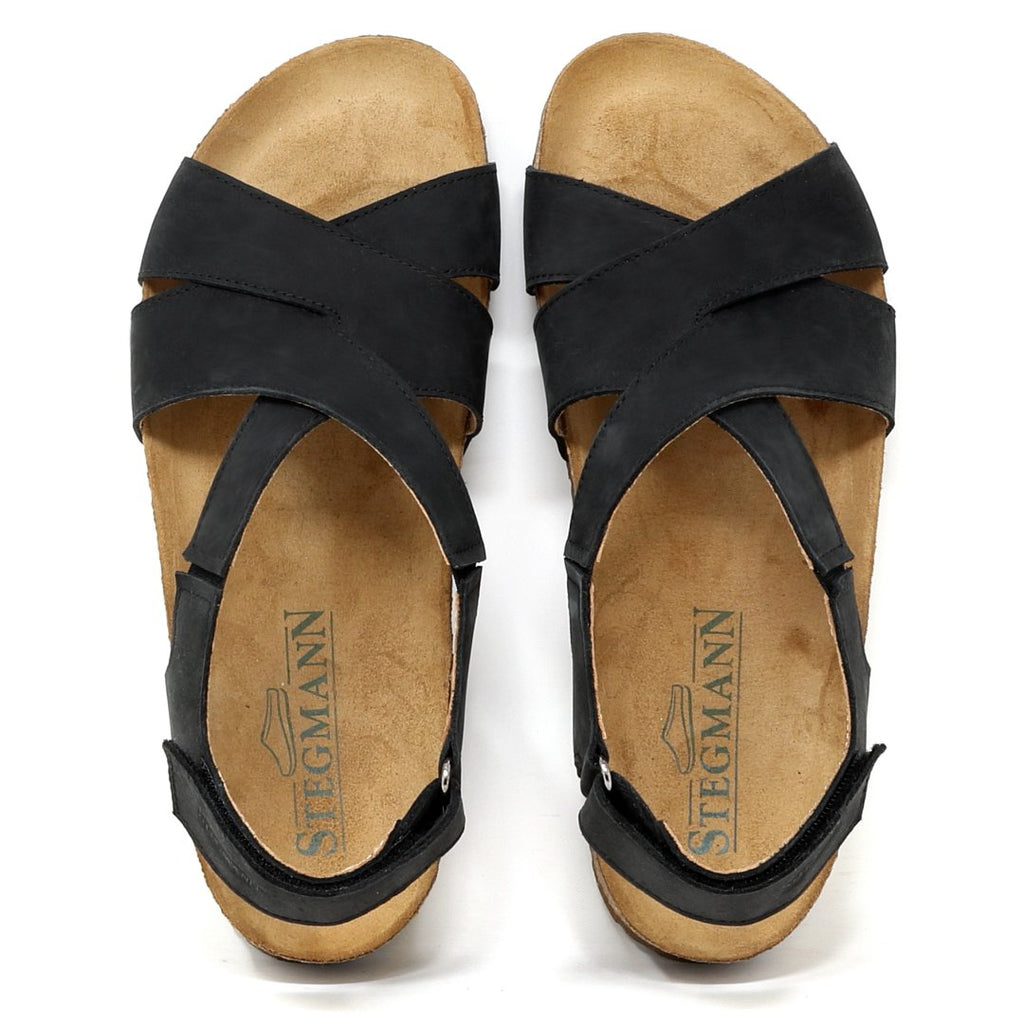 The Women's Hannah Leather Sandal - Medium features a black strappy design with cork soles, a Stegmann logo on the insoles, and a cushioned suede footbed for added comfort. It offers superior arch support, ideal for all-day wear.