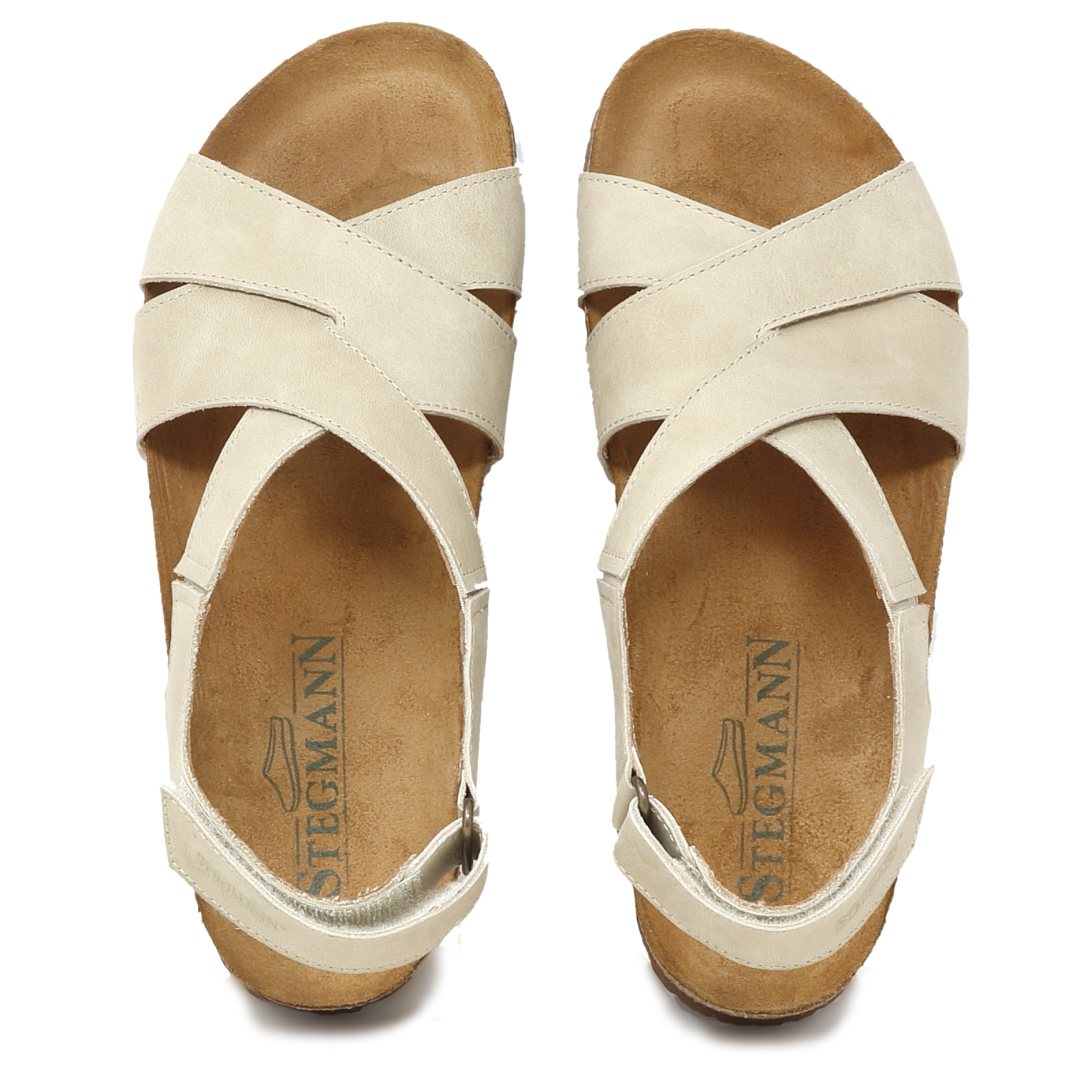 The Women's Hannah Leather Sandal - Medium in beige offers a cushioned suede footbed with arch support, a cork footbed, heel strap, and strappy design for comfort and style. The sandals feature the "Stegmann" logo for added elegance.