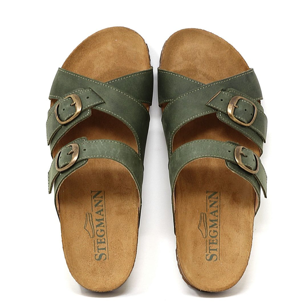A pair of "Women's Heidi Leather Sandal - Medium" in green with adjustable straps, brown buckles on a white background, featuring an ultra-cushy footbed and the "Stegmann" logo on the insoles.