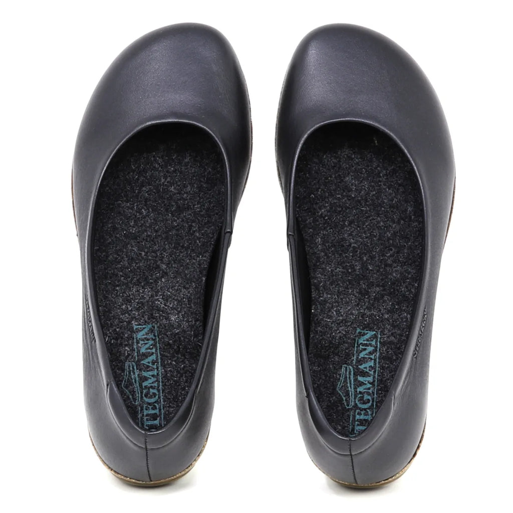 The Women's Helene Ballet Flat is a black leather shoe with rounded toes, seen from above. Each features a grey insole with blue Tegmann branding and subtle arch support for comfort.