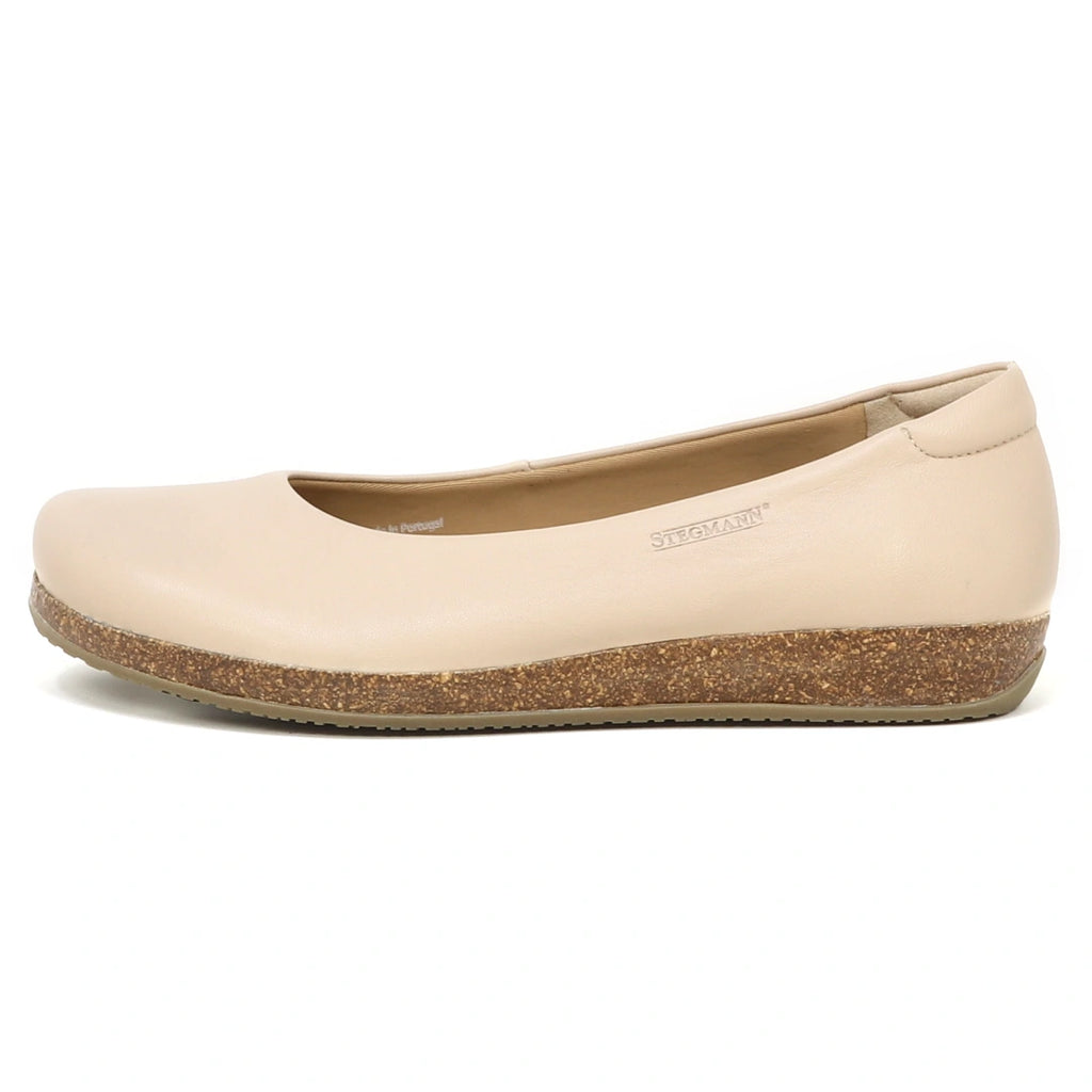 The Women's Helene Stretch Leather Ballet Flat, shown in side profile against a white background, features a beige color, rounded toe, cork-textured sole, and a bunion-friendly design for extra comfort.