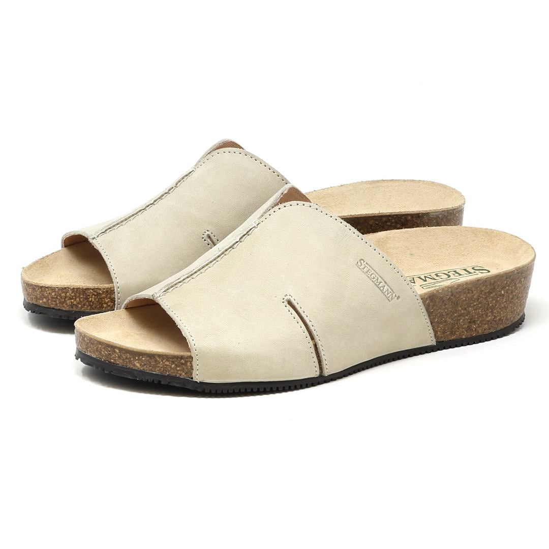 The Women's Layna Leather Wedge Sandal in beige features an open toe design, a low cork wedge heel, and a cushioned suede footbed with a brown insole for enhanced comfort.