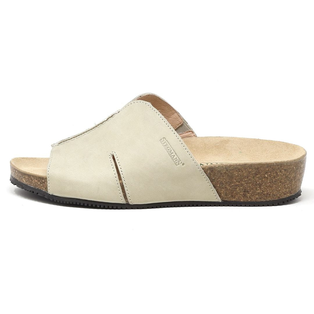 The Women's Layna Leather Wedge Sandal offers a beige slide design with a sustainable cork wedge sole, black rubber outsole, and cushioned suede footbed. The brand name is subtly embossed on the side for an elegant touch.