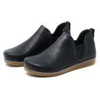 The Women's Lieben Leather Chelsea Boot is a black slip-on with closed toes, elastic side panels, brown textured soles, and a cozy wool felt lining, shown on a white background.