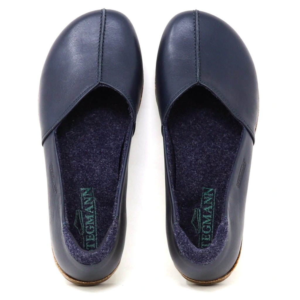 A pair of Women’s Liesl Leather Skimmer shoes in dark blue, featuring a wide toe box, visible stitching, soft gray insoles, and the brand name “Tegmann” printed inside.