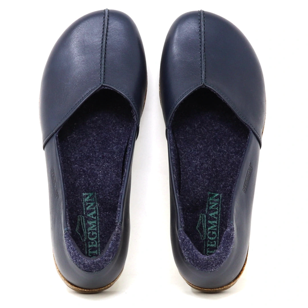 A pair of Women’s Liesl Leather Skimmer shoes in dark blue, featuring a wide toe box, visible stitching, soft gray insoles, and the brand name “Tegmann” printed inside.