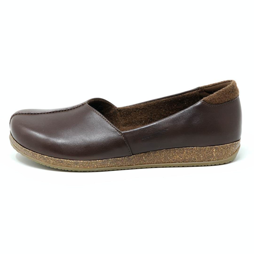 The Women's Liesl Leather Skimmer is a brown leather slip-on flat with a cork sole, supportive arch, and wide toe box, displayed in profile on a white background.