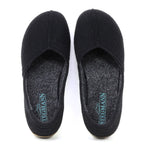 A pair of black Women's Liesl Wool Skimmer slippers with grey insoles, arch support, and "Stegmann" printed in blue on the heel.