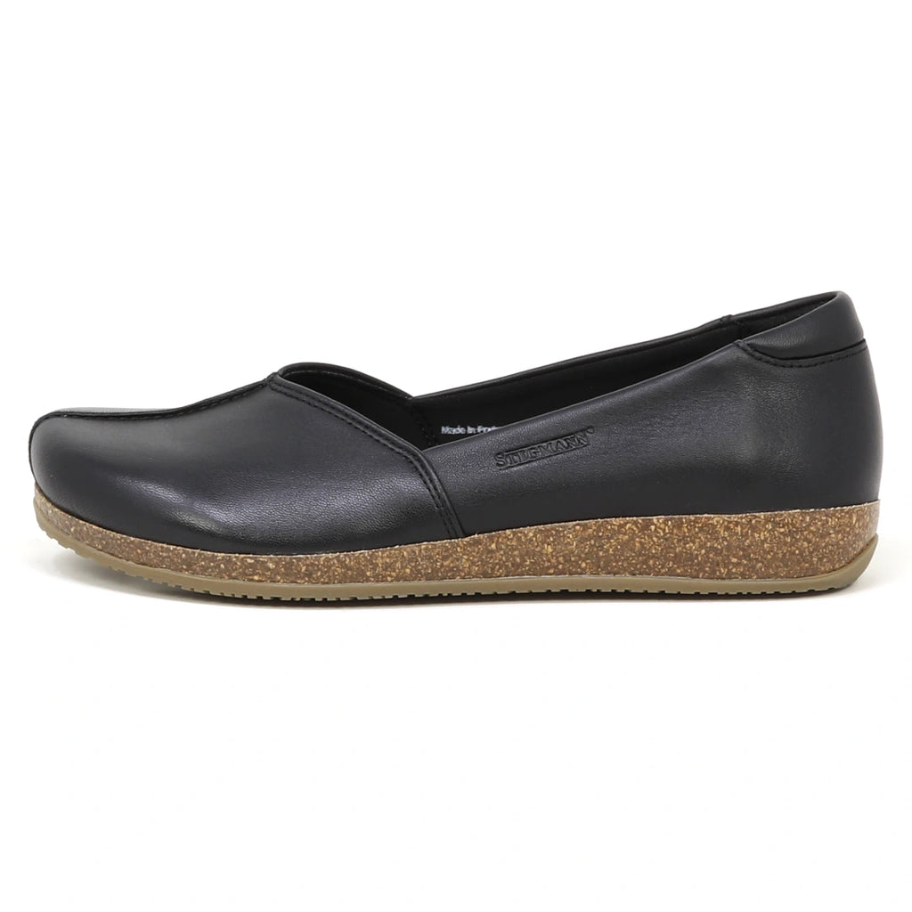 The Women's Liesl Stretch Leather Skimmer is a black slip-on flat with a brown cork sole and wide toe box, displayed in profile view on a white background.