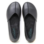 The Women's Liesl Stretch Leather Skimmer is a pair of black slip-on shoes made from buttery-soft leather, featuring a wide toe box, grey felt insoles, and "Stegmann" branding inside each shoe.
