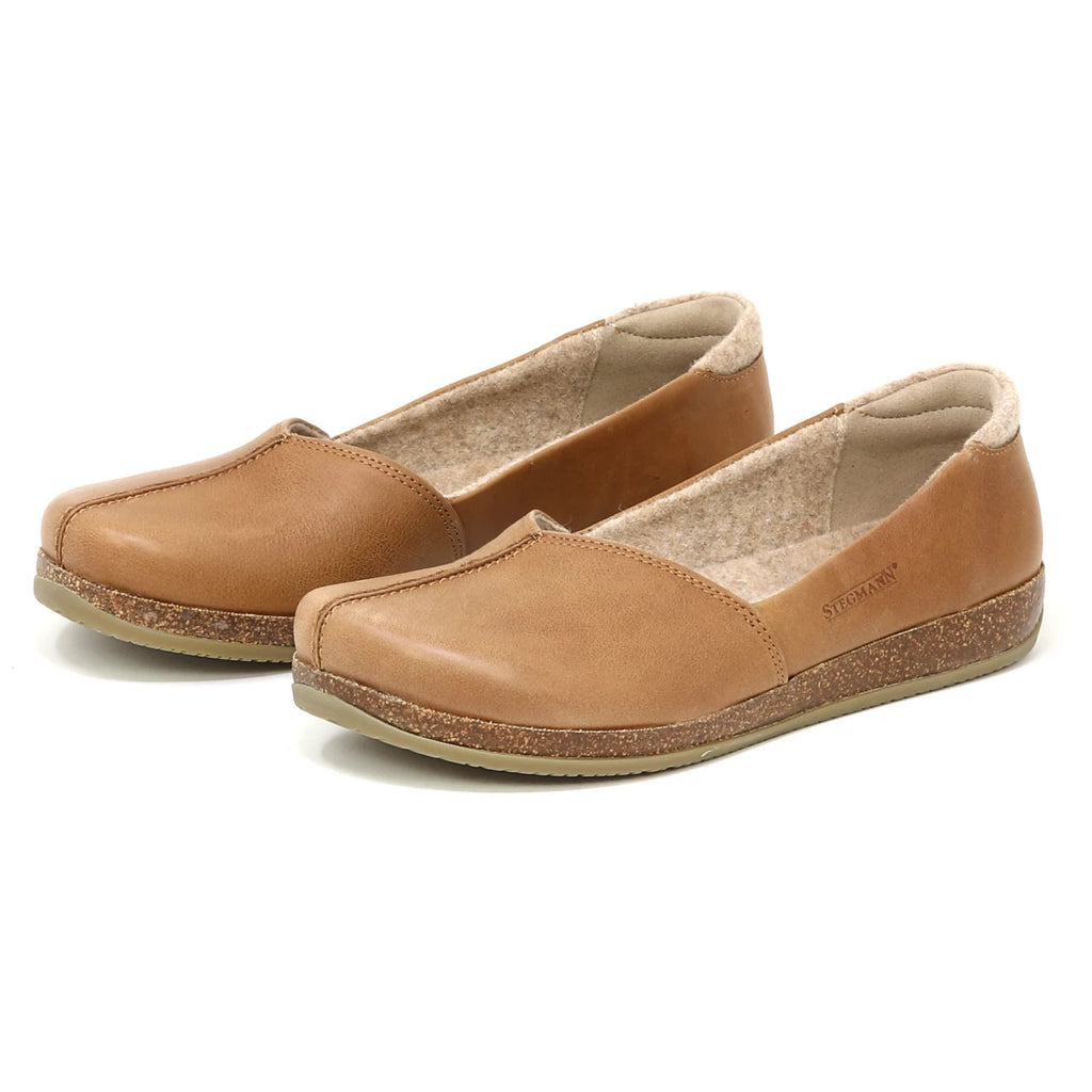 The Women's Liesl Leather Skimmer is a tan slip-on flat with cushioned insoles, wide toe box, arch support, rounded toes, and textured rubber soles.