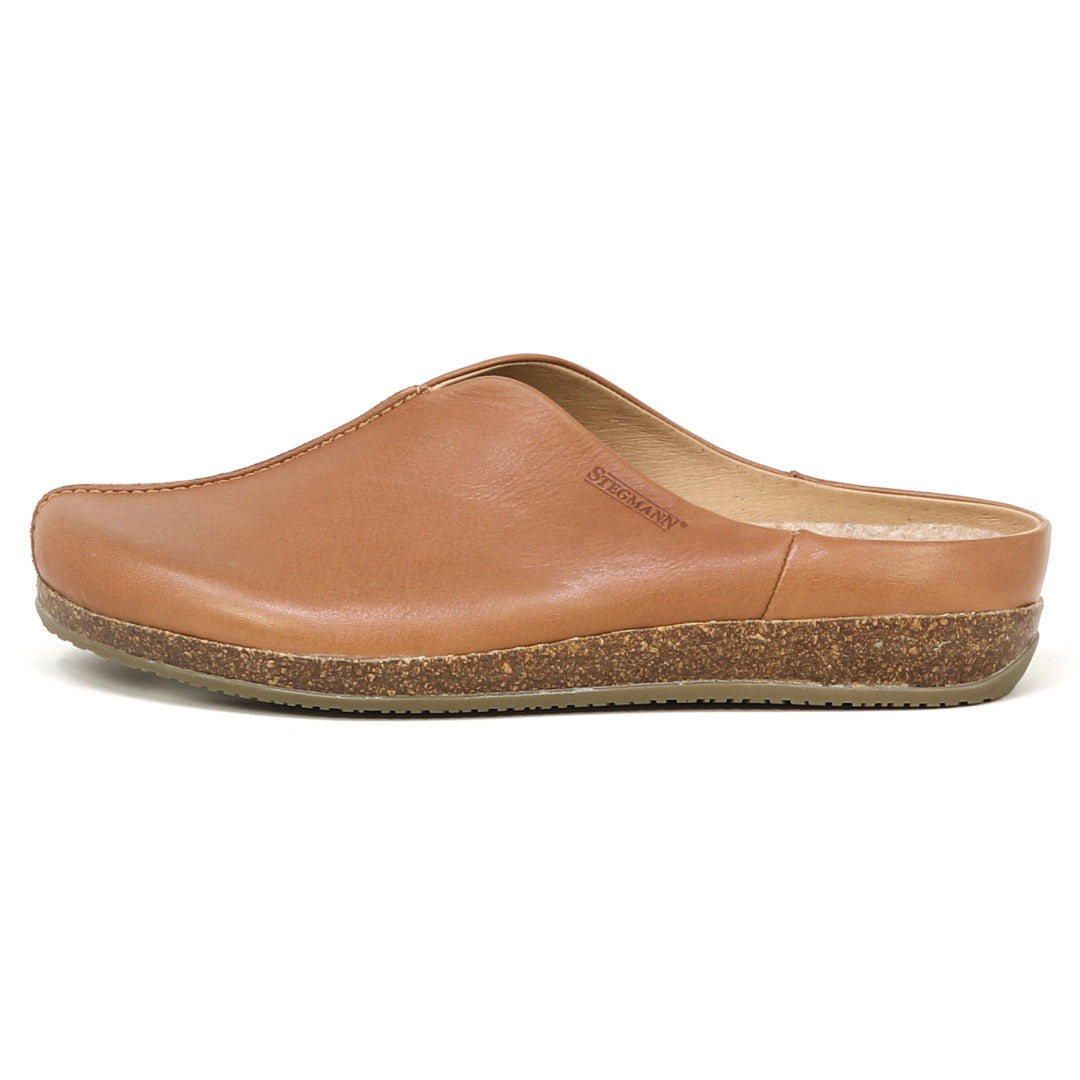 The Women's Maria Leather Mule is a tan leather slip-on with a cork latex sole, closed toe, and wide toe box, shown from the side.