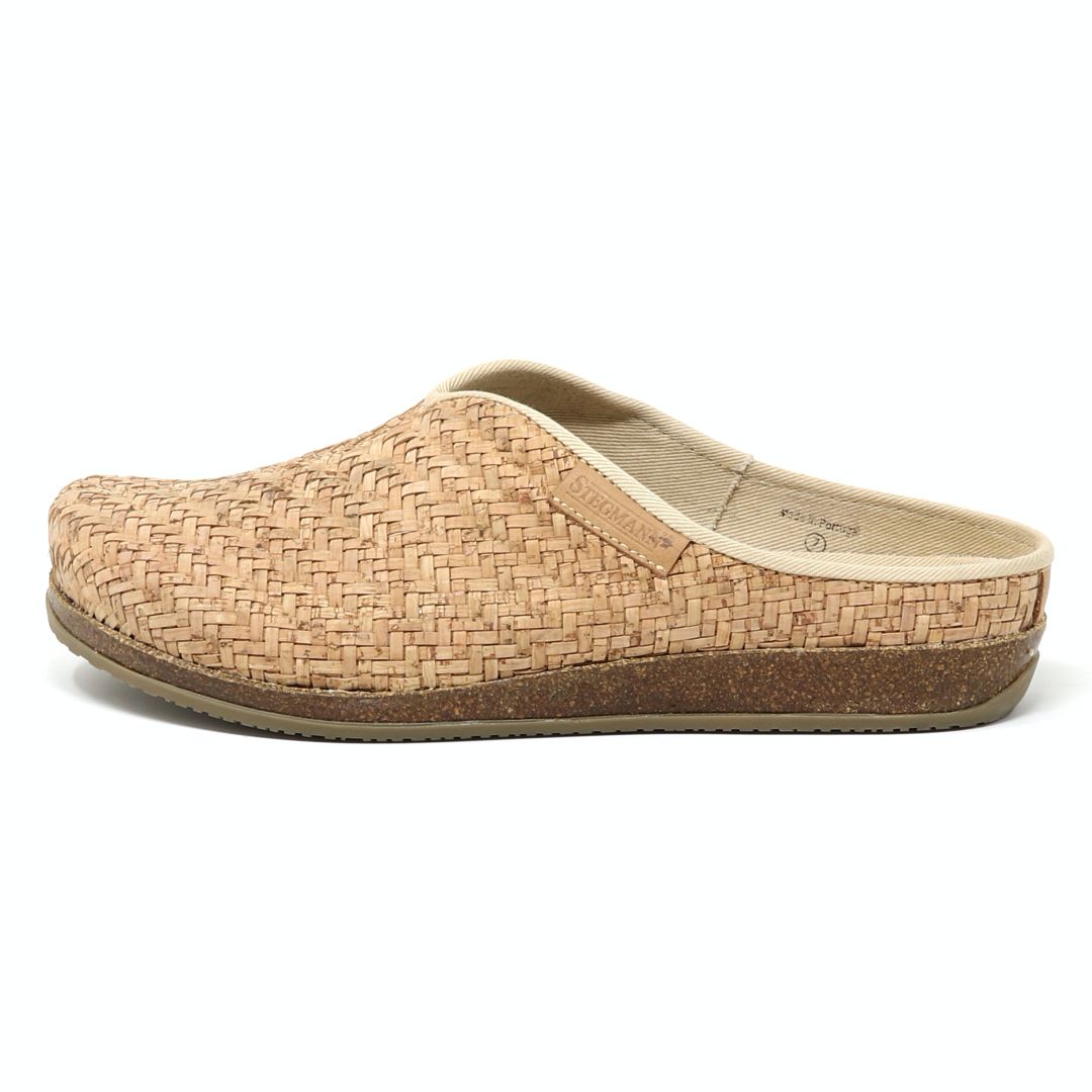 The Women's Maria Woven Cork Mule is a tan slipper with a sustainable cork sole and arch support. Featuring a closed toe and open heel, this stylish shoe is showcased from the side against a plain white background.