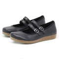 A pair of Women's Marielle Stretch Leather Mary-Jane shoes in black, featuring two buckle straps and cork-textured soles, crafted from stretch leather for added comfort, positioned side by side on a white background.
