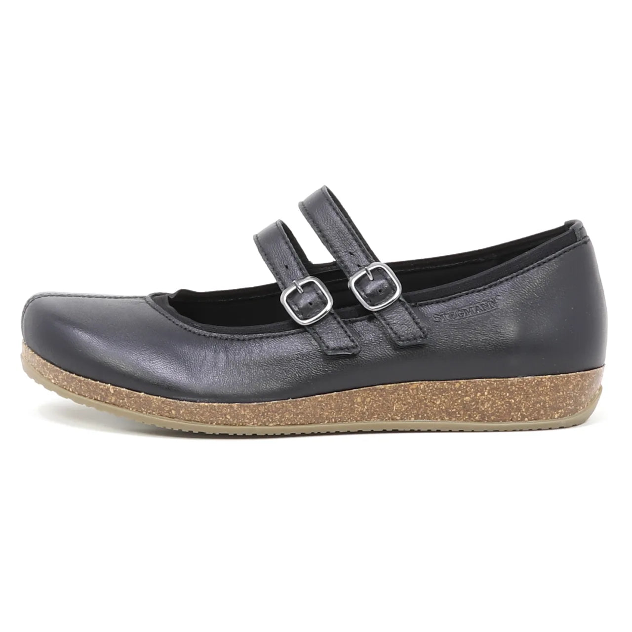 The Women's Marielle Leather Mary-Jane is a black stretch leather shoe with double buckle straps and a cork-textured flat sole, shown in side view against a white background, offering comfortable arch support for all-day wear.